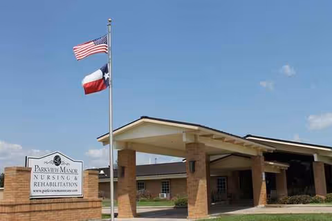 Exterior view of Parkview Manor Nursing and Rehabilitation entrance with brick columns and flags.