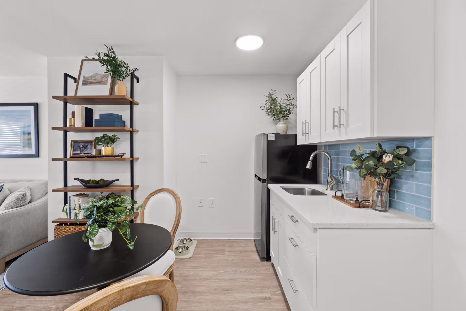 Modern white kitchen at Walden Place Senior Living with blue tile backsplash and dining table.