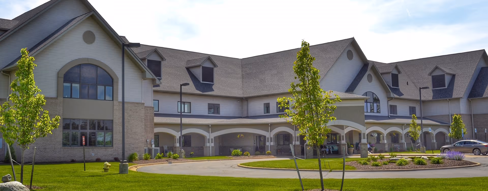 Front exterior of Delta Retirement Center showing a large two-story building with a covered entrance, landscaped lawn, and circular driveway.