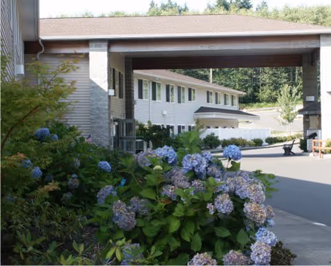 Front exterior of Westhaven Villa Assisted Living with a covered entry and blooming hydrangeas.