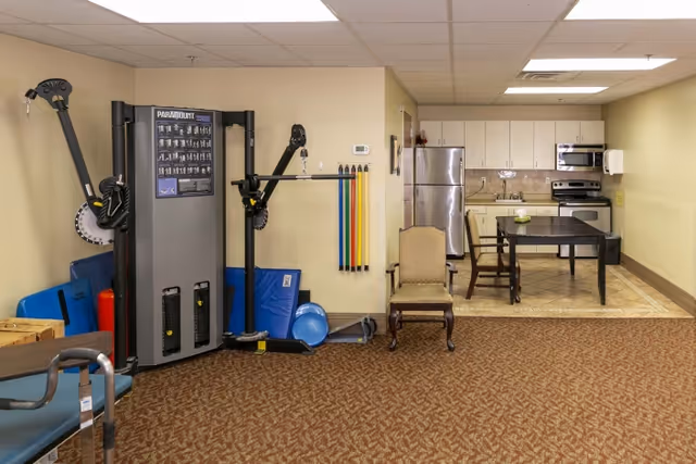 Multi-purpose interior room with exercise equipment on the left and a kitchenette with a dining table and chairs on the right.