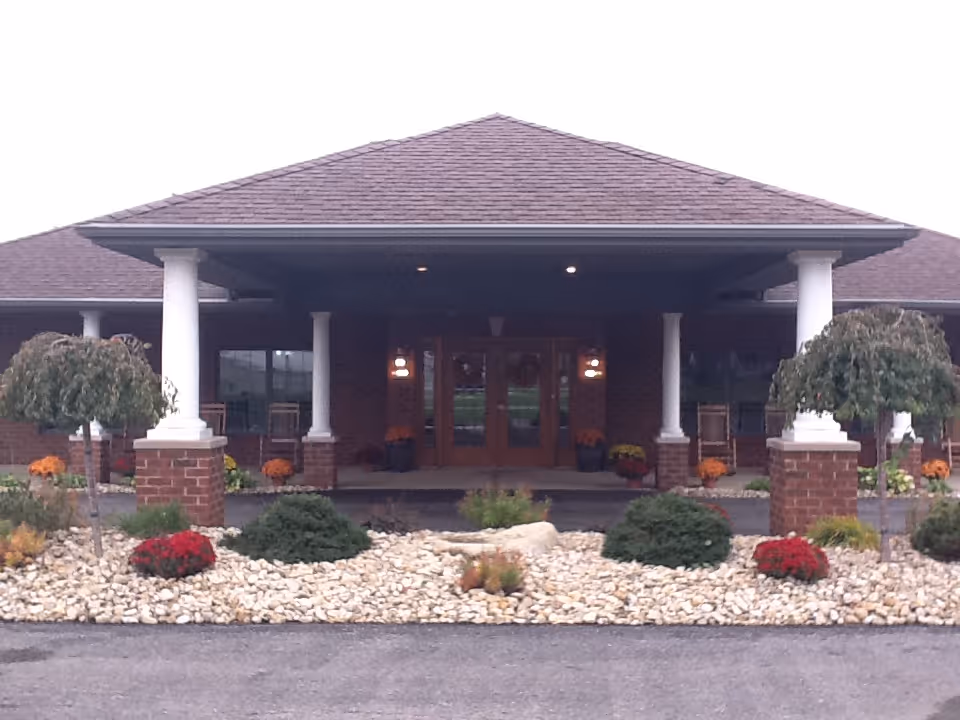 Front entrance of Westbrook Assisted Living & Memory Care with pillars and landscaped rocks.