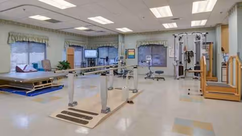 Interior rehab gym in a senior facility with parallel bars and equipment.