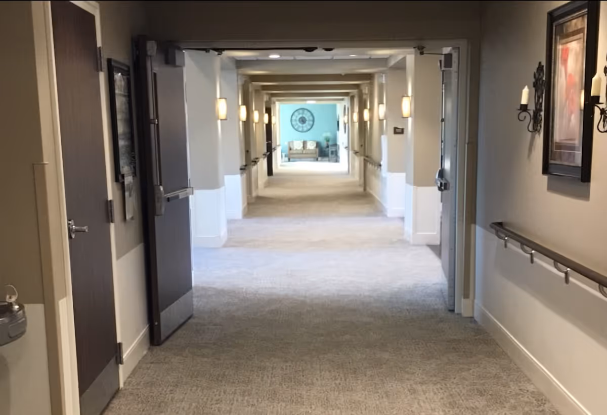 Long carpeted interior hallway with handrails and wall sconces leading to a seating area at the far end.