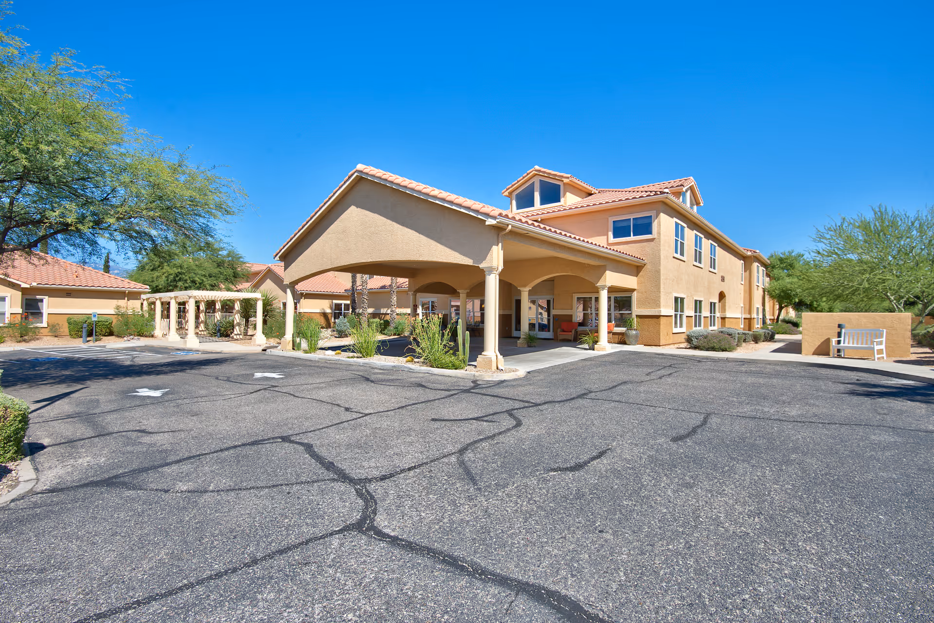 Exterior view of Sierra Del Sol Assisted Living facility showing a two-story building with a covered entrance, surrounded by trees and clear blue sky.