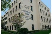 Exterior view of Meadow Park Rehab & Healthcare building with trees and blue sky.