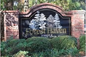 A brick sign for Forest Haven Nursing & Rehabilitation Center surrounded by green bushes and trees in the background.