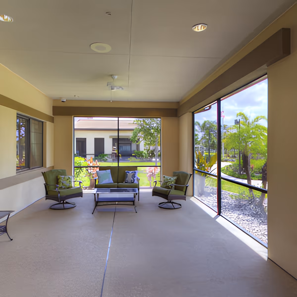 Screened outdoor seating area with chairs, a loveseat, and a coffee table overlooking landscaped grounds.