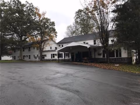 Exterior view of Narrowsburg Homes showing a covered entrance and surrounding parking lot.