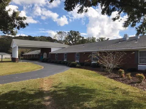 Single-story brick senior living facility with a covered entrance driveway and well-kept front lawn.