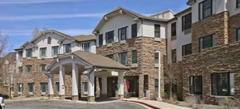 A multi-story senior living facility with stone facade and a covered entrance.