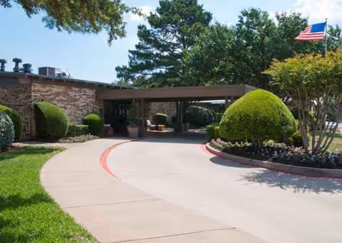 Avir at Grapevine front entrance with drive, shrubs, and flag.