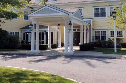 Exterior view of Orchard Hill Sudbury Assisted Living entrance with a white columned porte-cochere.