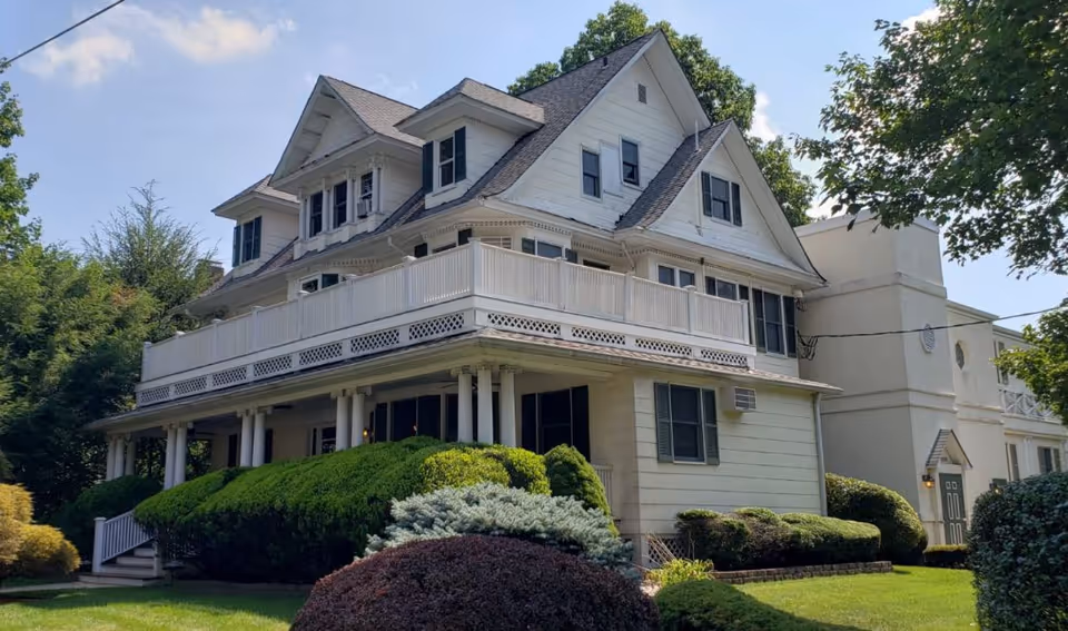 White multi-story senior residence with wraparound balcony and manicured landscaping.