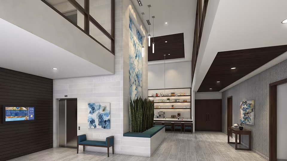 Modern senior living facility lobby with high ceilings, an elevator, a seating bench, decorative plants, abstract artwork on the walls, and a small bar or coffee station with shelves of bottles and glasses.