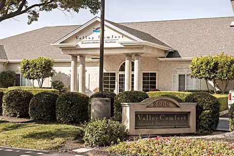 Front exterior of Valley Comfort senior living facility with entrance and manicured landscaping.
