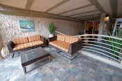 Outdoor patio seating area with striped couches, a glass coffee table, and railing.