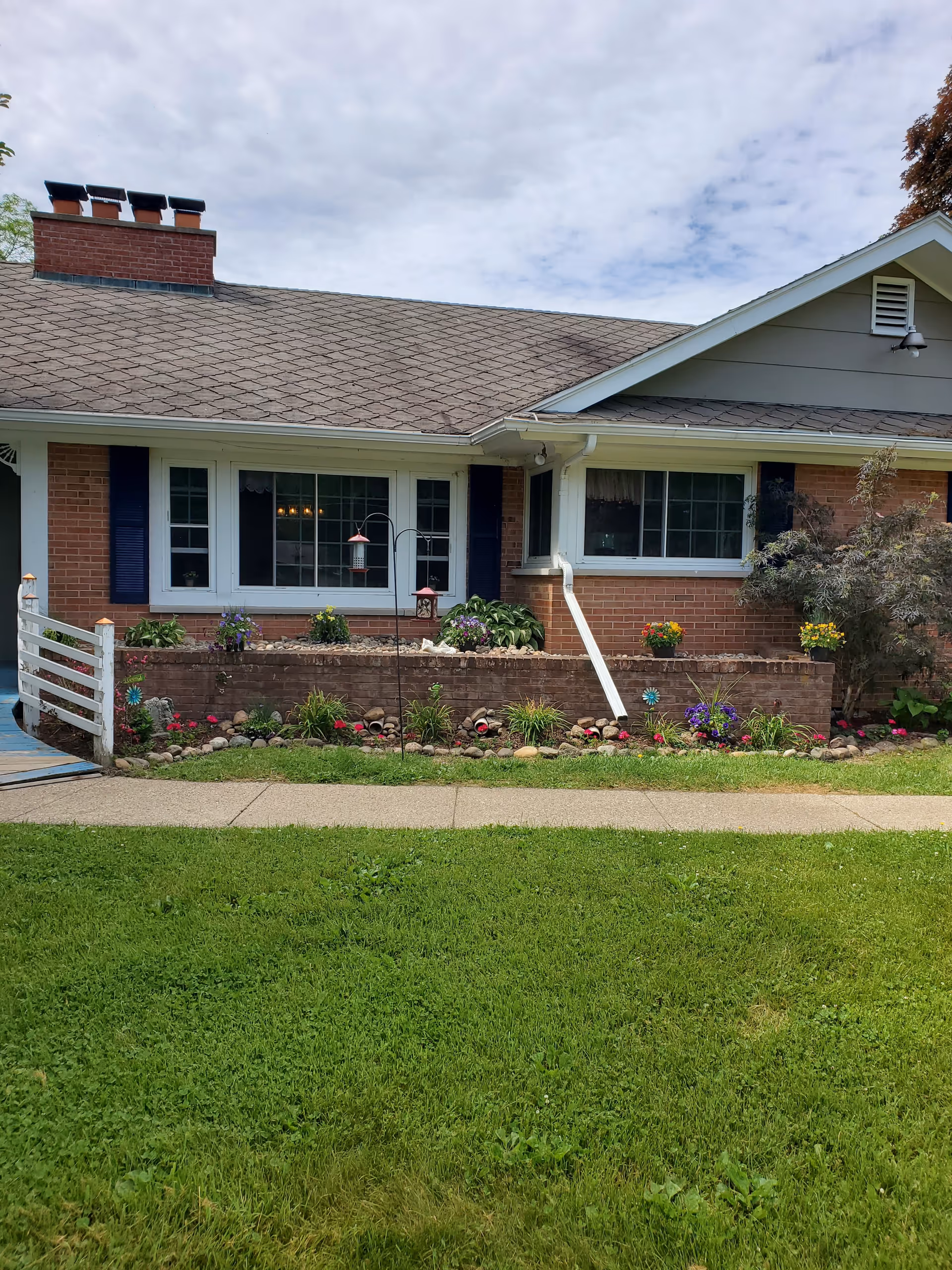 Front exterior of a single-story brick building with large windows, a raised flowerbed, and a grassy lawn.