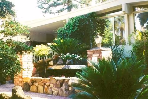Exterior view of Clarendon Senior Living entrance with landscaped planters and greenery.