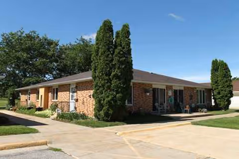 Exterior view of NewAldaya Lifescapes: a single-story brick senior living facility with entrance.