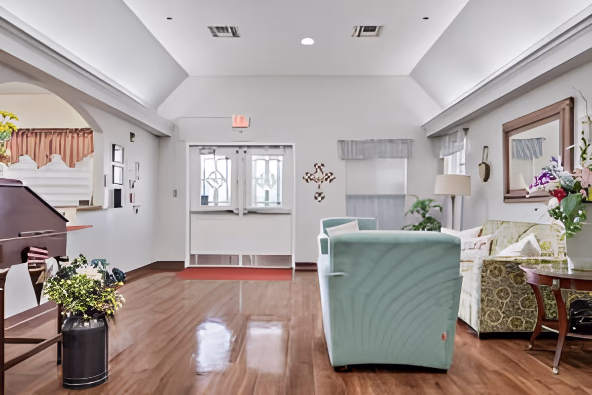 Bright reception lounge with mint-green armchairs, a patterned sofa, wooden floors and double glass entrance doors.