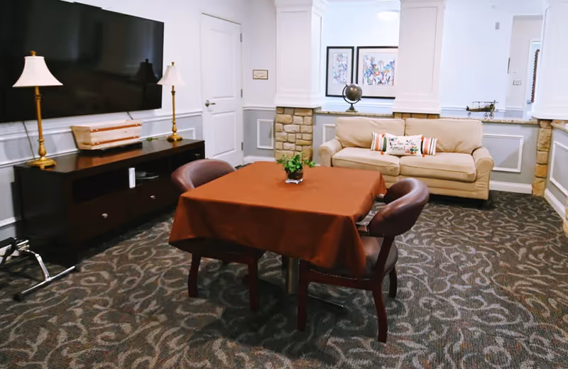 Common living area with a table, chairs, sofa, TV, and framed artwork.