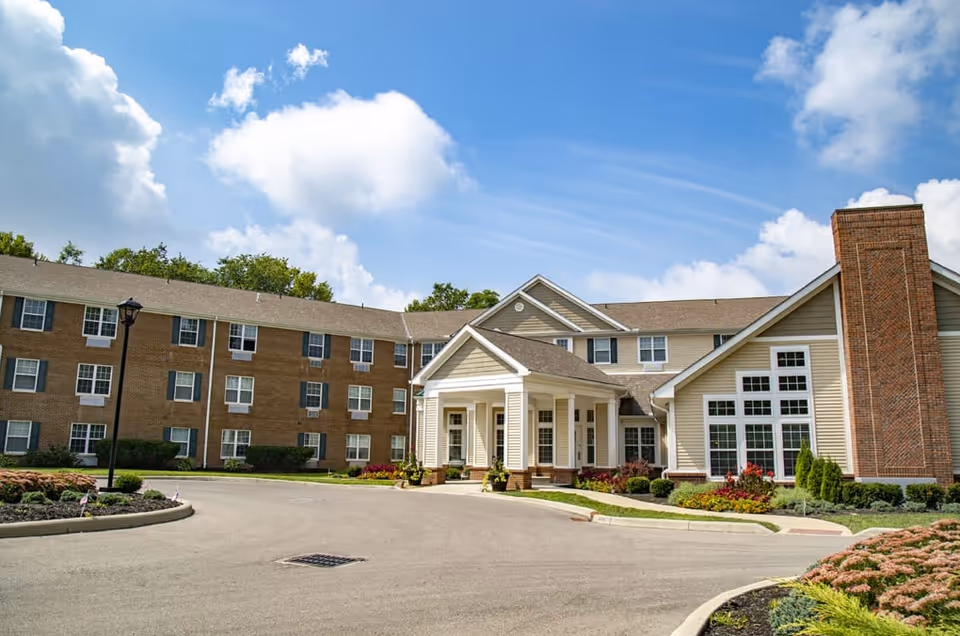 Wide view of a senior living facility exterior with a brick chimney and entrance.