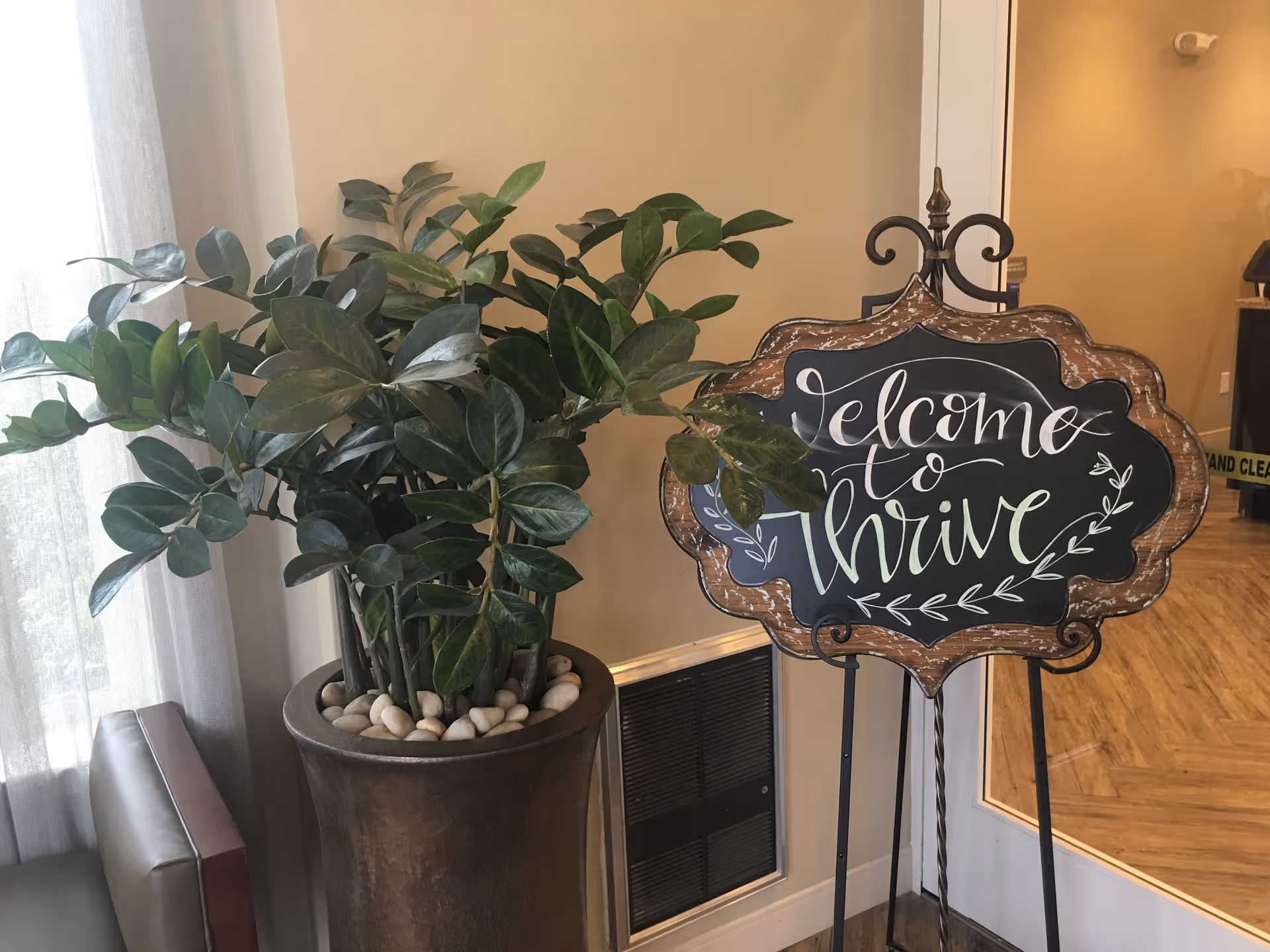 Indoor lobby featuring a large potted plant and chalkboard welcome sign.