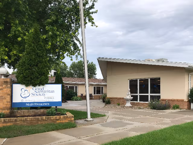 Front exterior of the Good Samaritan Society - Corsica showing the main entrance sign, flagpole, and a one-story building.
