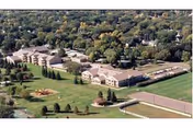 Aerial view of Avera Mother Joseph Manor Retirement Community showing multiple buildings surrounded by trees and greenery, with a playground and sports courts visible on the grounds.