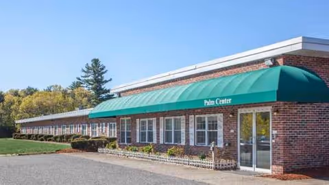 One-story brick building with a green canopy and glass doors labeled Palm Center.
