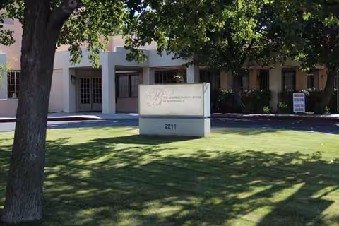Front exterior of The Rehabilitation Center of Bakersfield with a sign and green lawn.