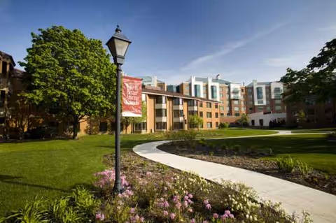 The front exterior of Encore Village of Schaumburg features a curved path and landscaped lawn.