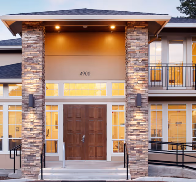 Exterior view of Murray Highland Memory Care entrance with stone pillars and double doors.