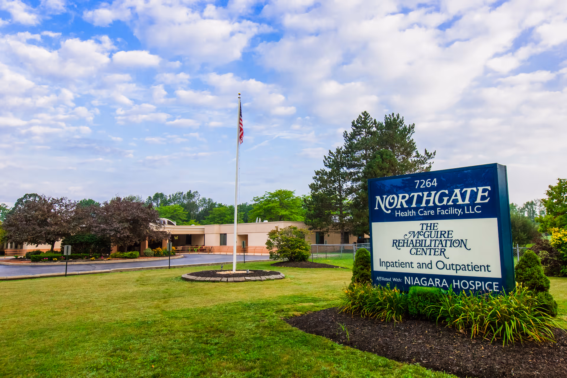 Front lawn and sign for Northgate Health Care Facility with the building and American flag in the background.