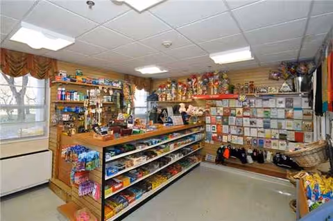 Interior of a senior living facility gift shop with shelves of snacks, toys, and greeting cards.