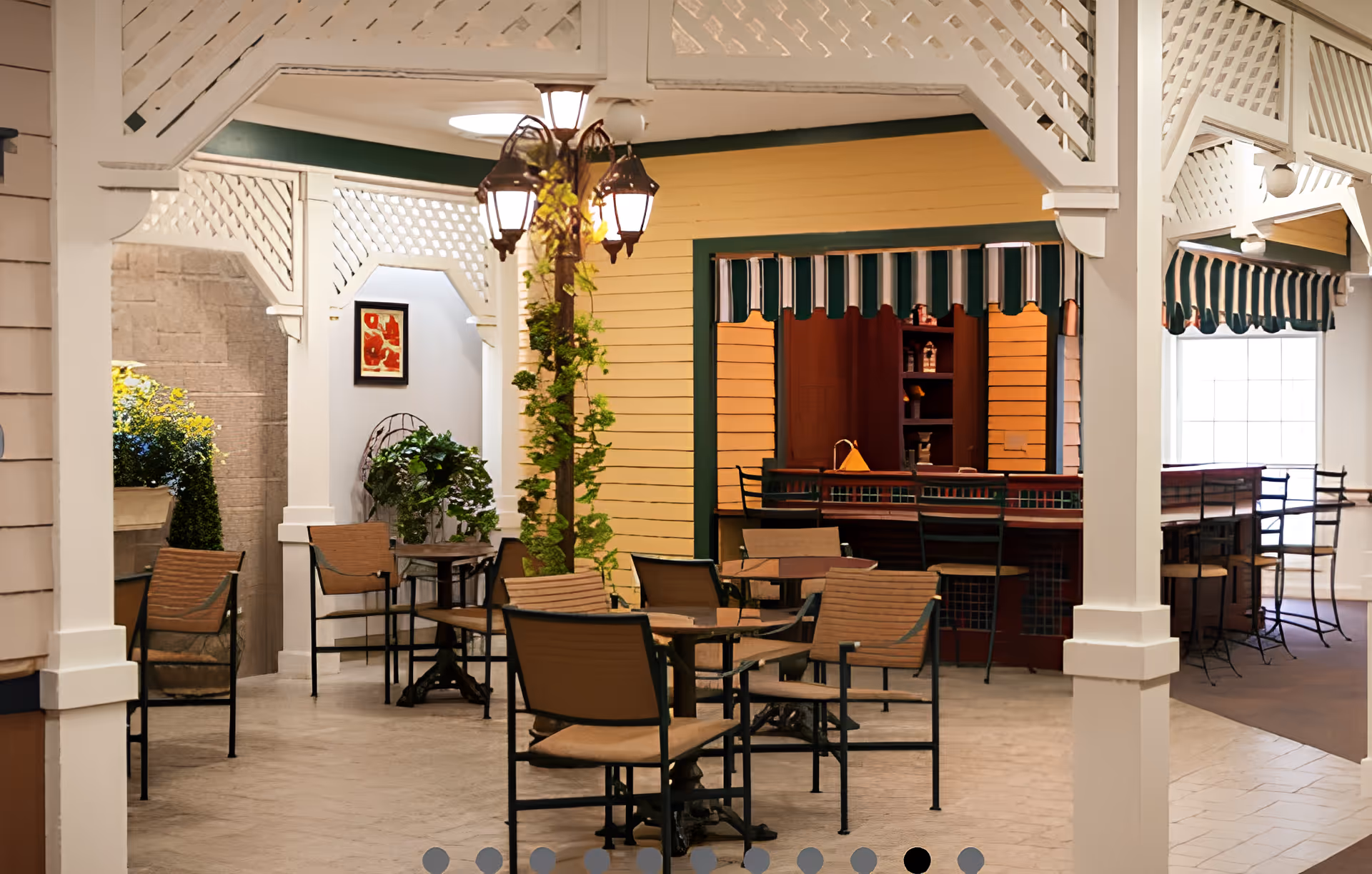 Indoor communal dining area with tables and chairs, a decorative lamppost, and a counter with striped awnings.