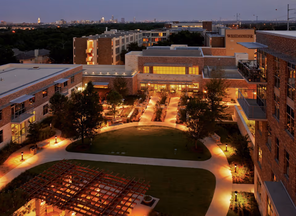 Aerial view of Westminster senior living campus at dusk, brick buildings framing a lit central courtyard.
