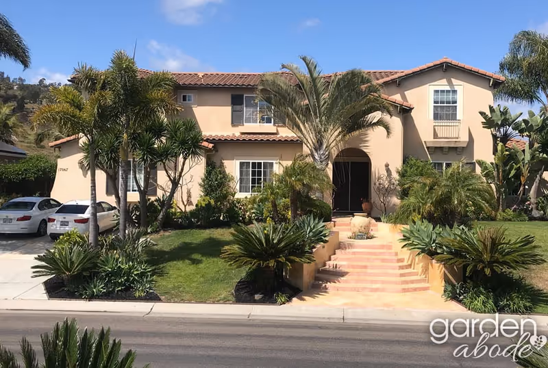 Two-story beige senior living facility with curved entry and tropical landscaping.