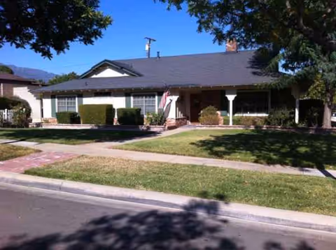 Single-story residential-style building with a front yard, shrubs, and an American flag.
