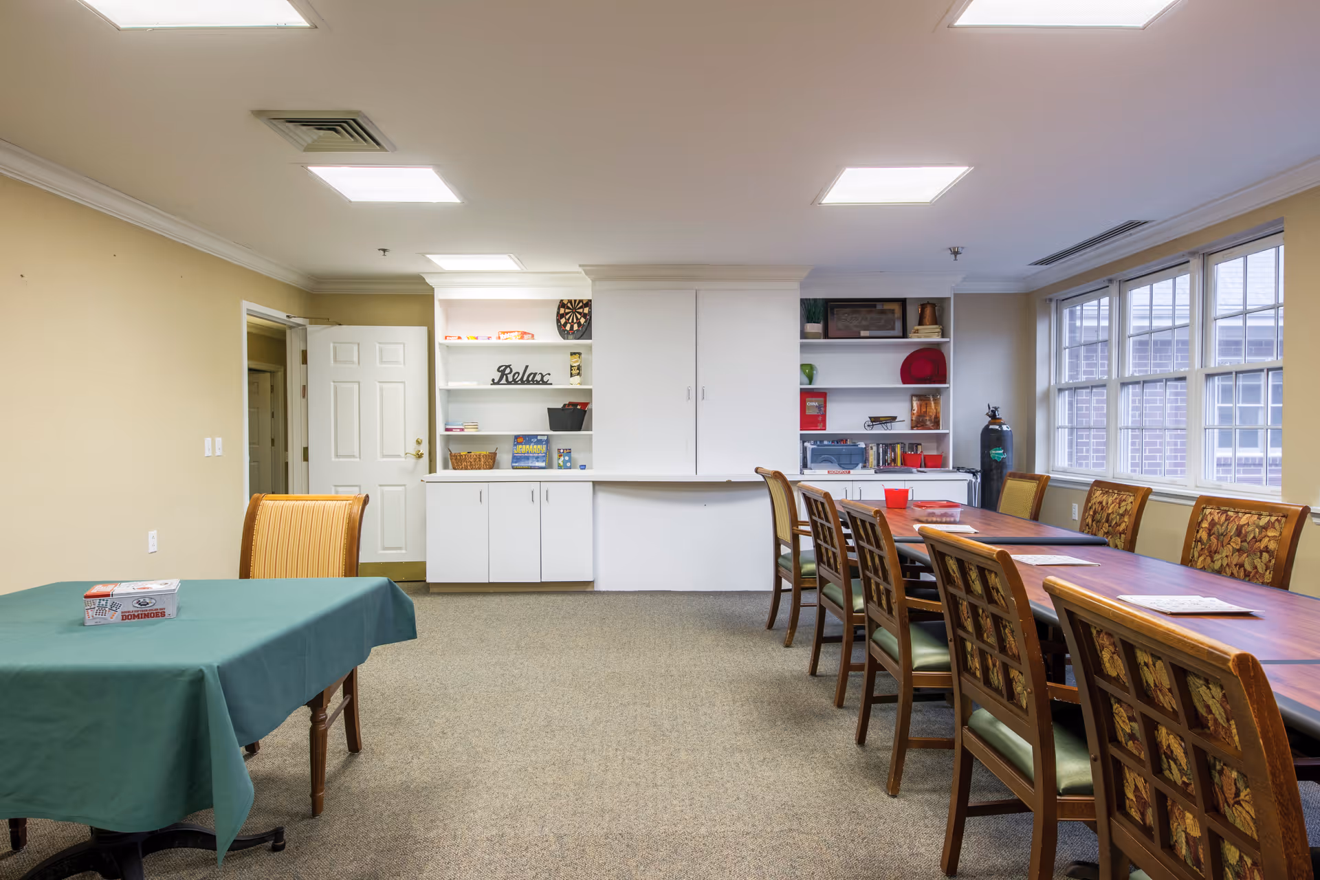A large dining room with a long table, chairs, and cabinets along the back wall.