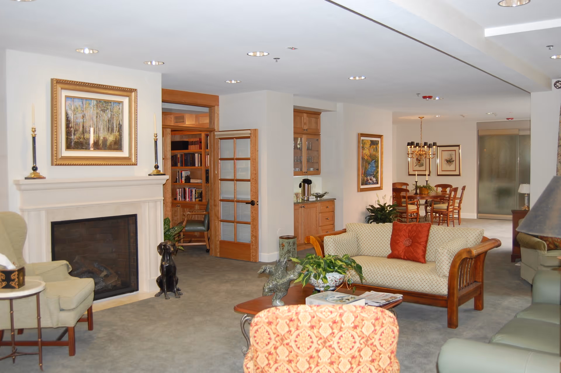 Spacious furnished lounge with a fireplace, seating area, coffee table, and a dining area visible in the background.