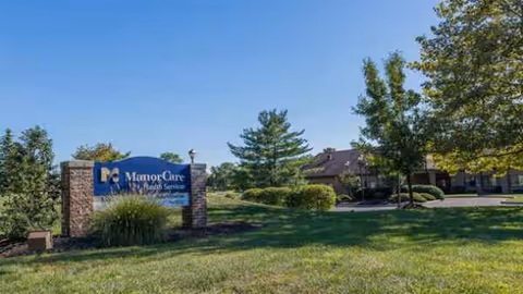 Outdoor view of a senior living facility sign beside a building with trees.