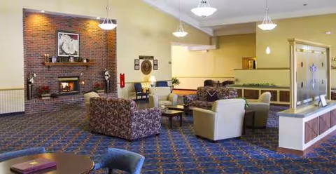 A spacious senior living lounge with a fireplace, comfortable seating, and a reception area.
