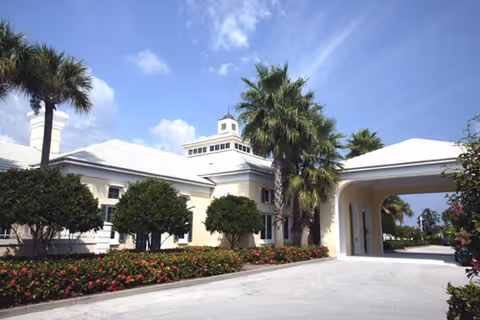 Exterior view of Somerset House at Oak Harbor, a white building with arches and palm trees.