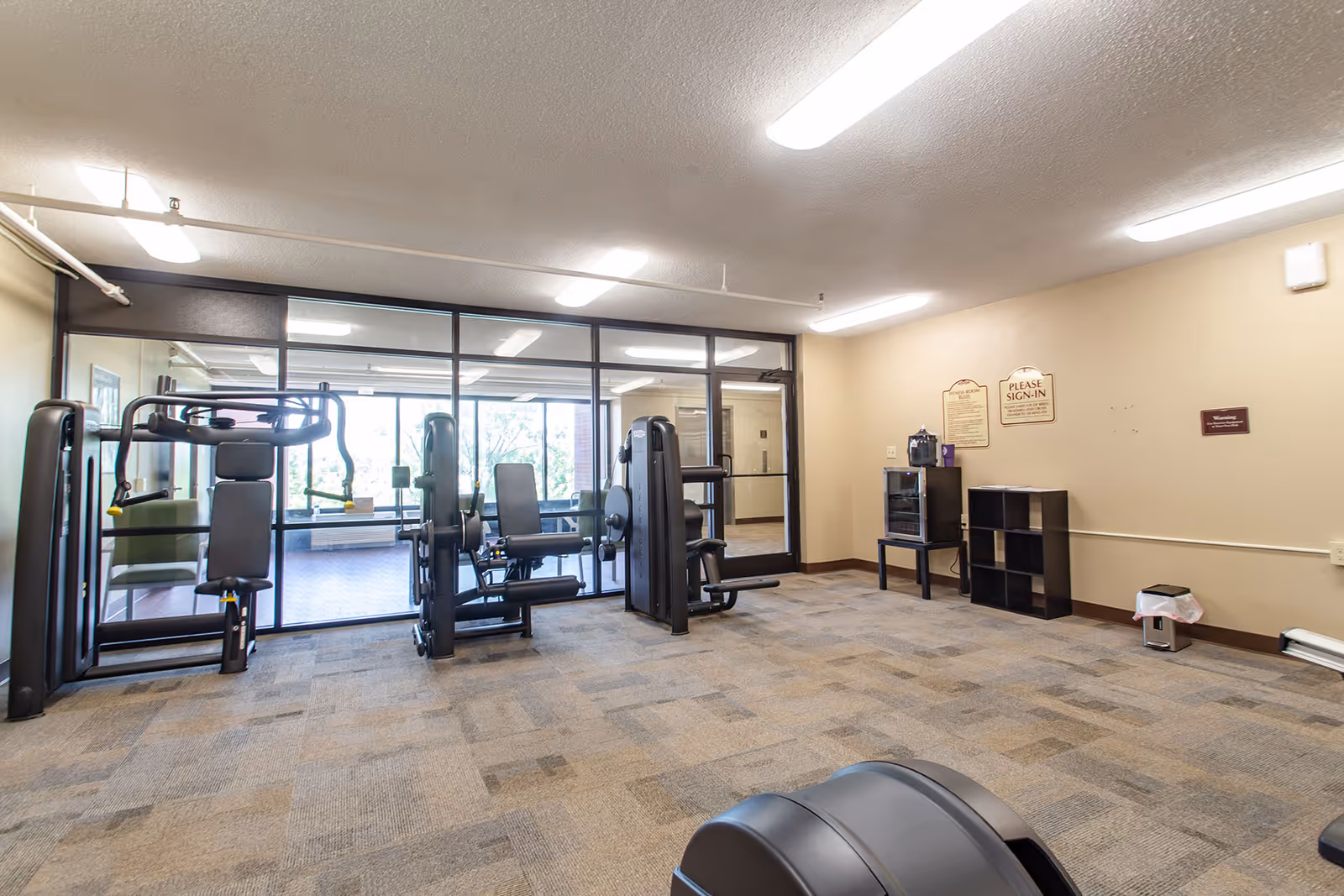 A gym area inside a senior living facility with weight machines and cardio equipment.