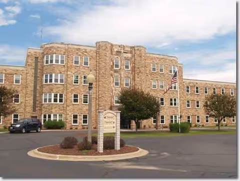 Front view of a stone Bell Tower Residence Assisted Living building with circular driveway.