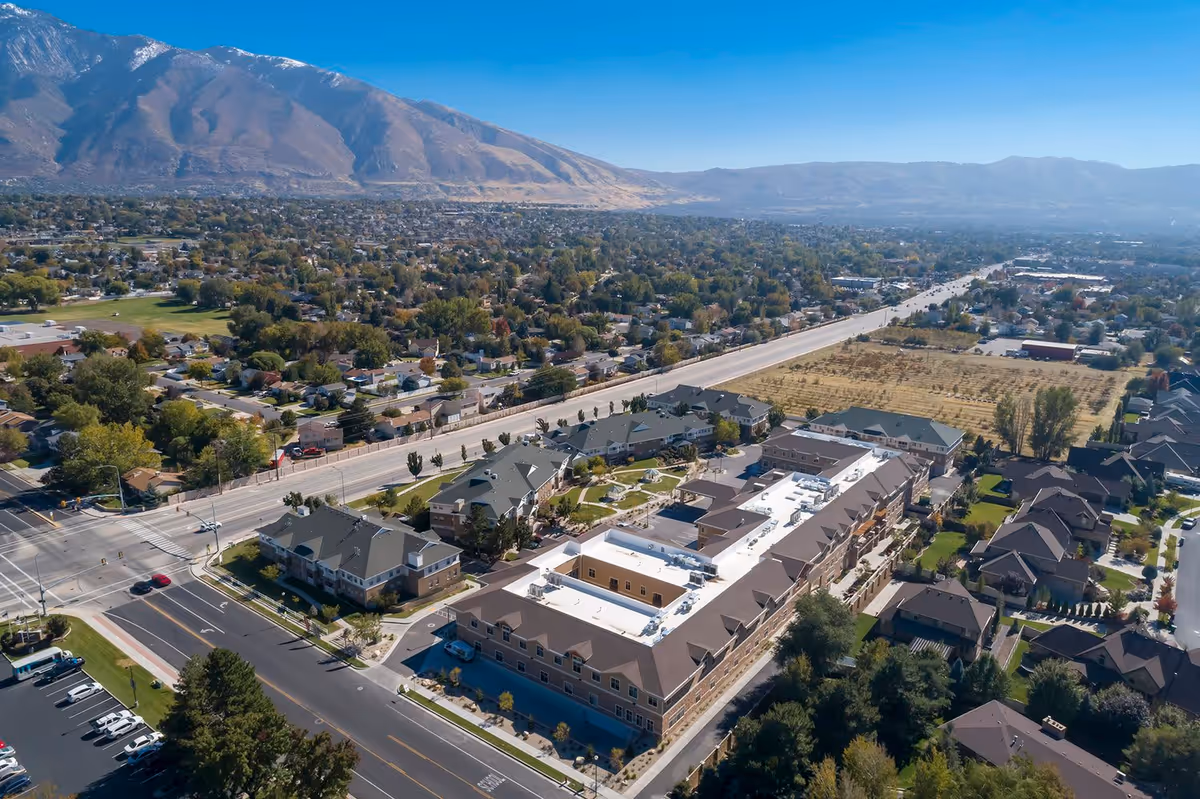 Aerial view of Crescent Senior Living facility surrounded by residential neighborhoods, with a mountain range in the background under a clear blue sky.