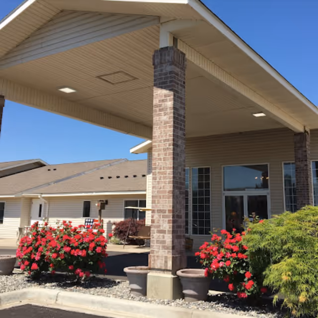 Exterior view of Green Lake Senior Living Amber Hills entrance with brick columns and flowering bushes