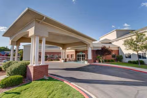 Covered entrance with columns and brick facade opens to a circular driveway.